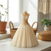 Ivory bridal gown-shaped candle with detailed floral lace bodice and full skirt on white surface.