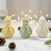 Set of three snowman-shaped candles in cream, sage green, and white, each wearing a knit hat and scarf.