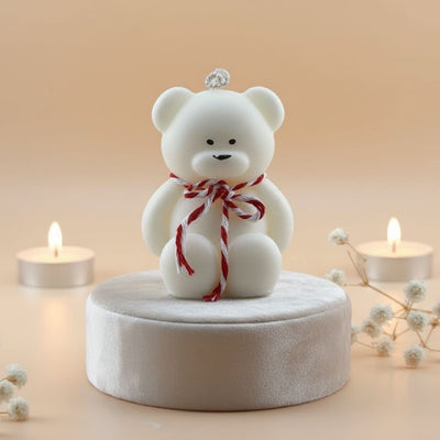 White teddy bear with a red ribbon on a beige background with candles and flowers.