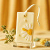 Creamy white soy wax sachet with a textured yellow and white daisy and pearl accents, hanging ribbon.