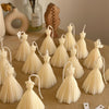 Set of cream bridal wedding dress candles with pleated skirt details on a wooden surface.